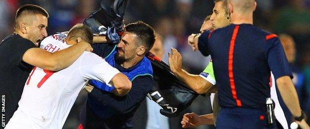 Serbia's Stefan Mitrovic is surrounded as he tries to pull down the Albanian flag