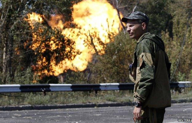 An armed pro-Russian separatist looks as flames erupt from a gas pipeline after a shelling in Donetsk (August 2014 file pic)