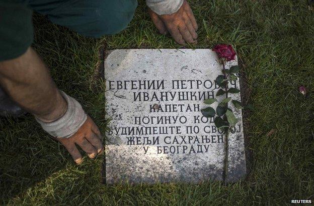 A man cleans the grave of a Soviet soldier at Belgrade's memorial cemetery, 13 October