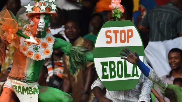 An Ivory Coast fan holds up a "Stop Ebola" placard