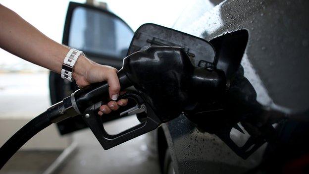 A woman pumps petrol into her car.