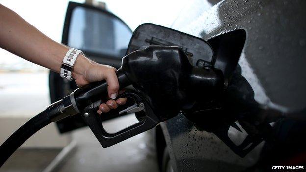 A woman pumps petrol into her car.