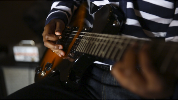 Close up of Aren Wilkins playing the guitar