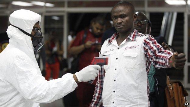 A Nigerian official uses a thermometer on a worker at Murtala Muhammed International Airport in Lagos, Nigeria on 6 August 2014