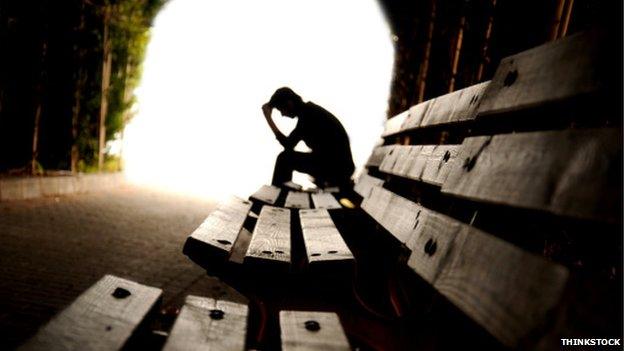 Man looking depressed in tunnel, with bright light at end of tunnel