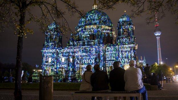 People looking at Berlin's cathedral, the Berliner Dom, lit up for a festival