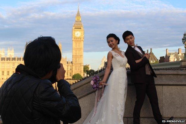 Couple pose for photographer (in shot) at the south end of Westminster Bridge