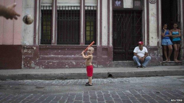 A child plays baseball with his father in front of his home in Havana (17 October 2014)