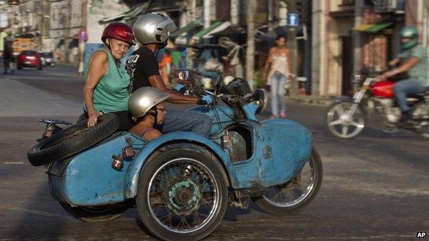 People ride in an Ural Soviet motorcycle in Havana, Cuba (9 October 2014)