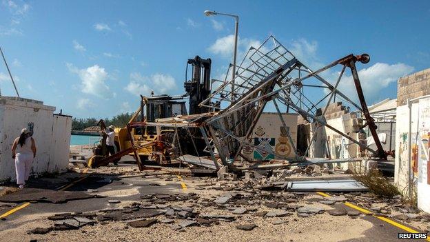 A woman walks around debris after Hurricane Gonzalo passed through the Royal Naval Dockyard, western Bermuda, October 18, 2014