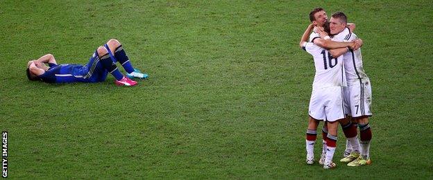 Sergio Aguero lies dejected on the turf as Germany celebrate winning the World Cup