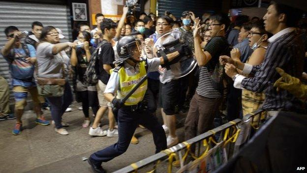 A policeman holding a baton advances towards pro-democracy protesters as they clash on a street in the Mong Kok district of Hong Kong early on 19 October 2014