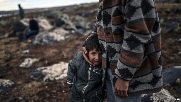 Kurdish boy Mohammed from Mizra village of Kobane watches with his father their village from the Turkish border in the southeastern village of Mursitpinar, Sanliurfa province, on 19 October