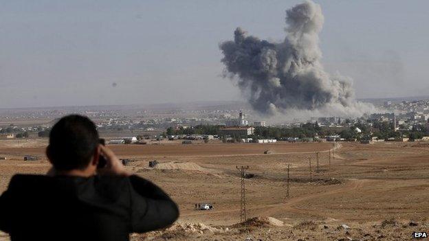 A man watches from a hill as smoke rises after an US-led coalition airstrike on Kobane, Syria, on the Turkish side of the border, near Suruc district, Sanliurfa, Turkey, 18 October 2014