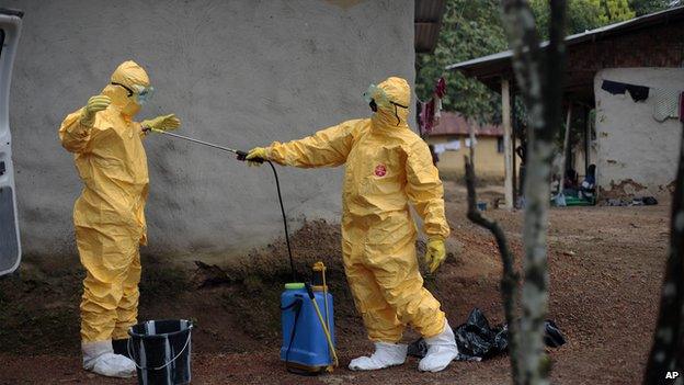 Medical workers disinfect each other's suits in Liberia