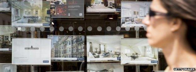 Woman passing estate agent's window