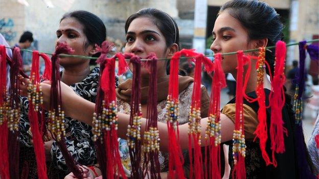 Pakistani women look at 'rakhi' (sacred thread) at a roadside shop ahead of the Hindu festival Raksha Bandhan in Karachi - August 2014