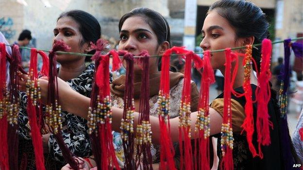 Pakistani women look at 'rakhi' (sacred thread) at a roadside shop ahead of the Hindu festival Raksha Bandhan in Karachi - August 2014