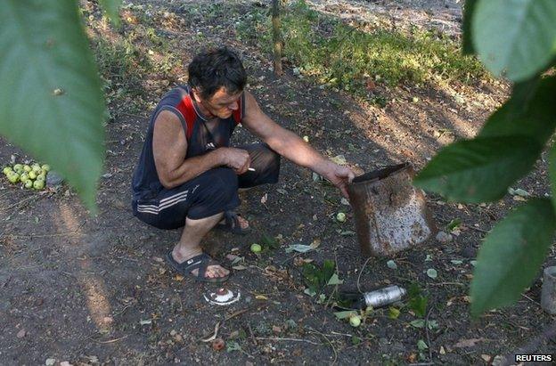 A man shows a dud cluster bomblet in Donetsk, Ukraine, 25 August