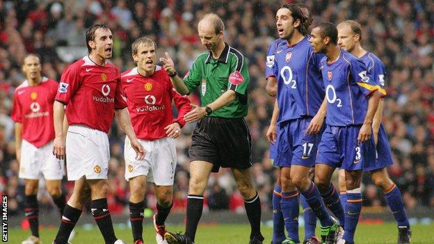 Manchester United and Arsenal players surround Mike Riley