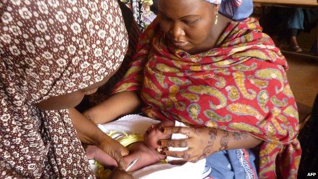 A health worker (L) vaccinates a child at a public health centre where children are being vaccinated against polio in Kano, northern Nigerian, on 13 February 2013