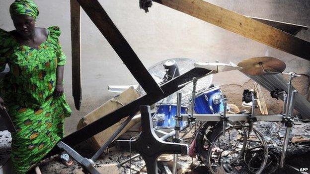 A woman walks past musical instruments belonging to the Redeemed Christian Church of God burnt by unidentified gunmen at Tudunwada district, Mubi in north-eastern State of Adamawa on 5 October 2012