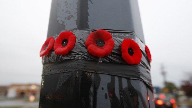 A raindrop falls from one of the poppies placed on a lamp post in the parking lot in front of a Service Canada building, where a suspected Islamic militant deliberately ran over two soldiers with his car (21 October 2014)