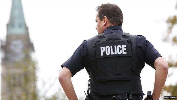 A police officer stands in front of the Peace Tower in Ottawa, Canada