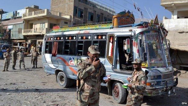 Pakistani security officials inspect the site of an incident were unknown assailants opened fire on a bus in Hazara Ganji area of Quetta, Pakistan, 23 October 2014