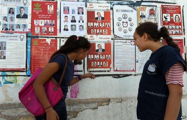 Tunisian girls look at election posters put up on a street ahead of the parliamentary election in the Tunis suburb of Ariana on October 21, 2014.