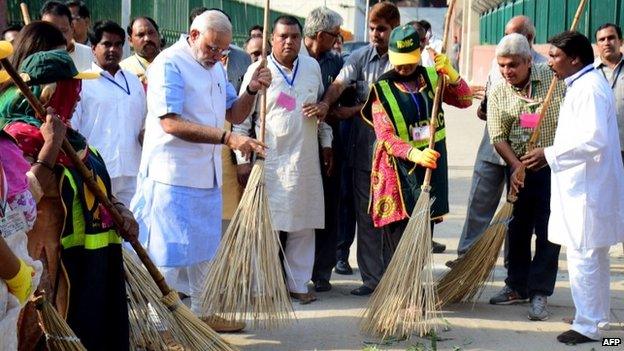 Indian Prime Minister Narendra Modi (L) sweeps a street in a residential colony in New Delhi on October 2, 2014.