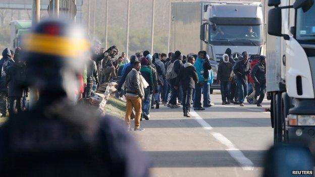 Migrants are chased by French policemen near lorries in Calais, France on 22 October 2014