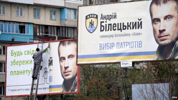 A worker changes a poster on a pre-election billboard with a portrait of candidate Andriy Biletsky (23 Oct)