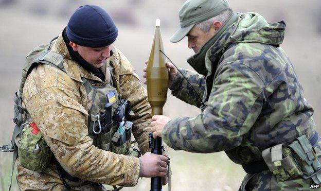 Ukrainian soldiers load a grenade launcher at their position in the village of Bugas in the Donetsk region, on 24 October 2014