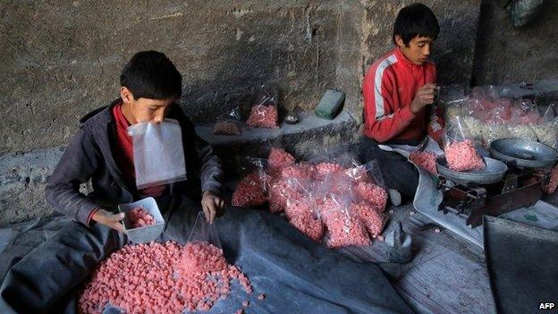 Afghan labourers sort traditional sweets as they work at a factory in Ghazni province, 14 September 2014