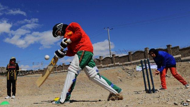 File photo: Afghan girls play cricket on the grounds of a school in Herat, 9 March 2014