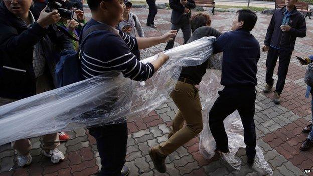 Protesters, center left, and center, take away the balloon from North Korean defector, right, during a rally in Paju, north of Seoul, South Korea, Saturday, Oct. 25