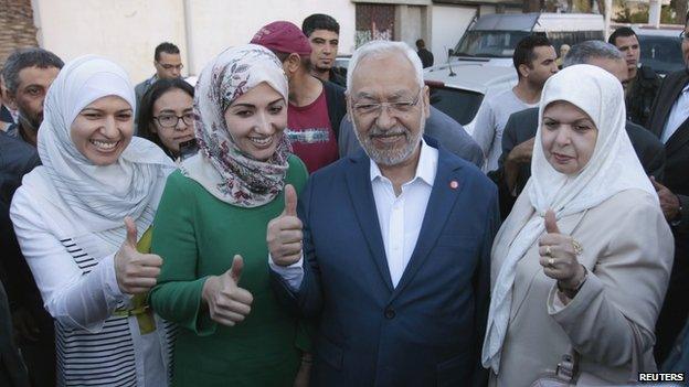 Rached Ghannouchi (C), leader of the Tunisian Islamist party Ennahda, gestures with his wife and two daughters Yousra (L) and Soumaya (2nd L) at a polling station during an election in Tunisia October 26, 2014