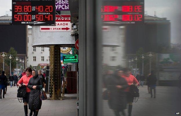 People walk past money exchange offices in Moscow, Russia, Monday, 6 Oct 14