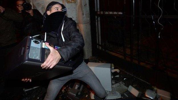 A protester throws the base of an old computer at the headquarters of the Fidesz governor's party in Budapest (26 Oct)