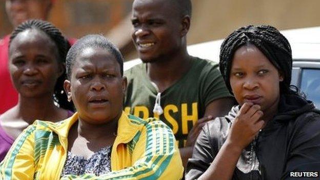 Neighbours of Kelly Khumalo, girlfriend of killed fooball player Senzo Meyiwa, look on outside her home in the township of Vosloorus, 27 October 2014