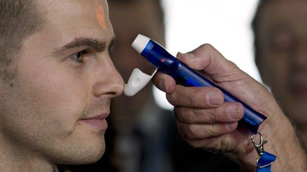 Man at Roissy-Charles-de-Gaulle airport having his temperature taken