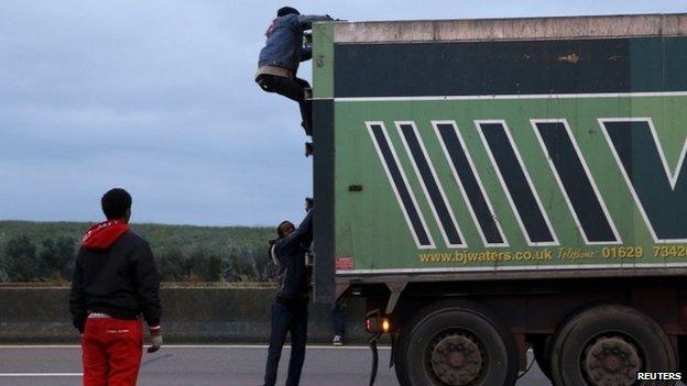 Migrants try to enter a lorry on its way into the ferry terminal at Calais earlier this month