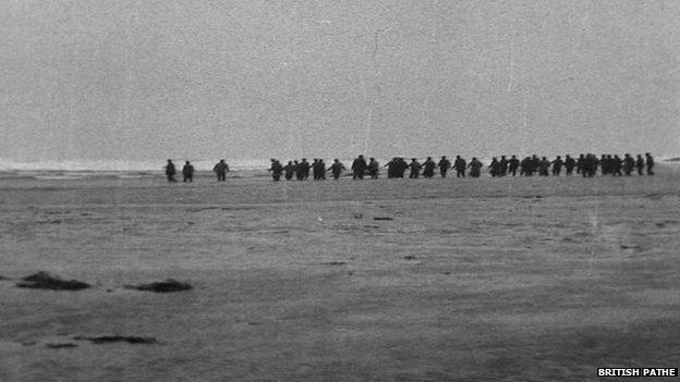 Crowds forming a line on the beach to wade out to help survivors of the Rohilla