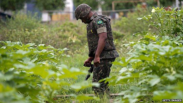 Brazilian soldier searches for buried weapons in a slum Rio de Janeiro, Brazil