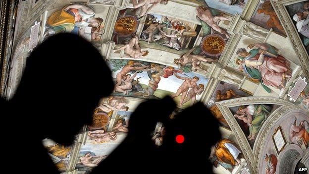 A journalist takes a picture inside the Sistine Chapel after its new lights and AC are installed