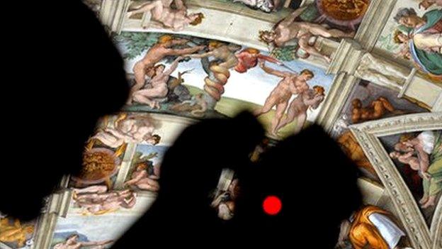 A journalist takes a picture inside the Sistine Chapel after its new lights and AC are installed