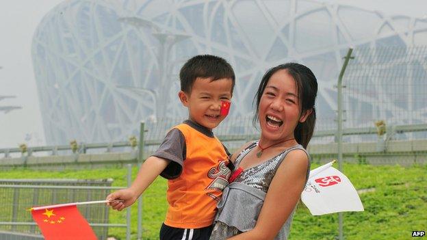 Chinese tourists pose outside the Olympic Bird's Nest Stadium in Beijing on 10 September, 2012