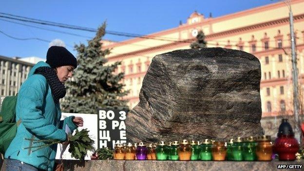 A woman places a candle and flowers at the memorial to the victims of Soviet-era political repression at the Solovky Stone monument, on Lubyanka Square in Moscow.