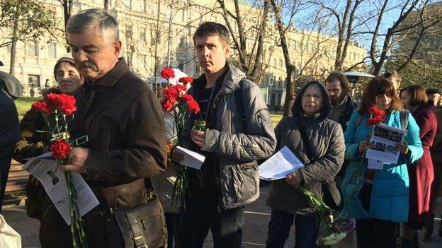 People queue to lay flower at a memorial for victims of Soviet-era political repression